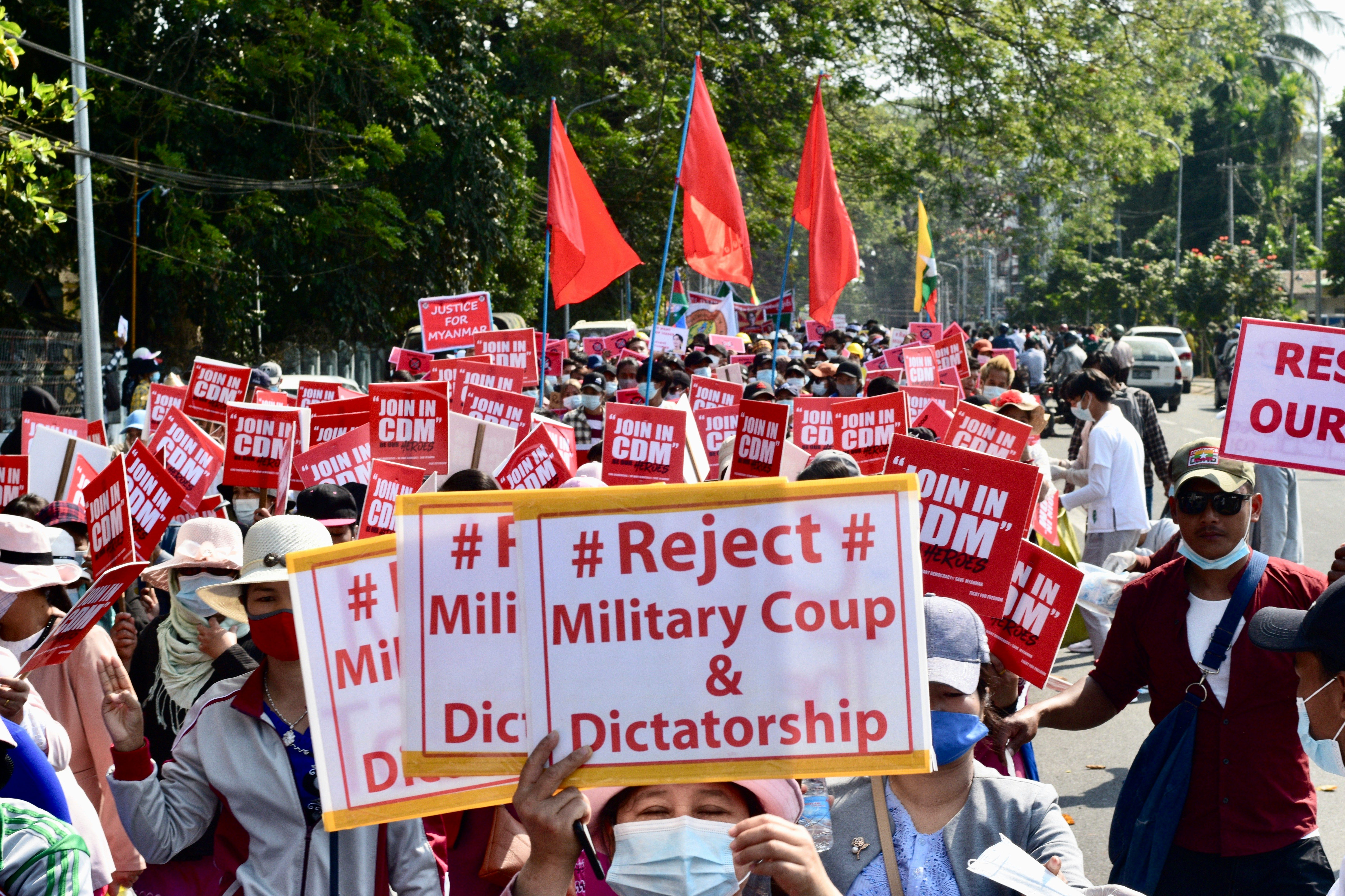 Pro-democracy protesters in Burma holding signs rejecting military coup and dictatorship
